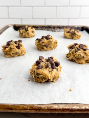balls of chocolate chip cookie dough on a parchment lined baking sheet.