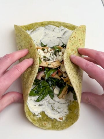 hands folding in the sides of a tortilla wrap.