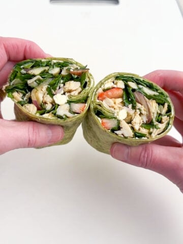 hands holding two halves of a tortilla wrap.