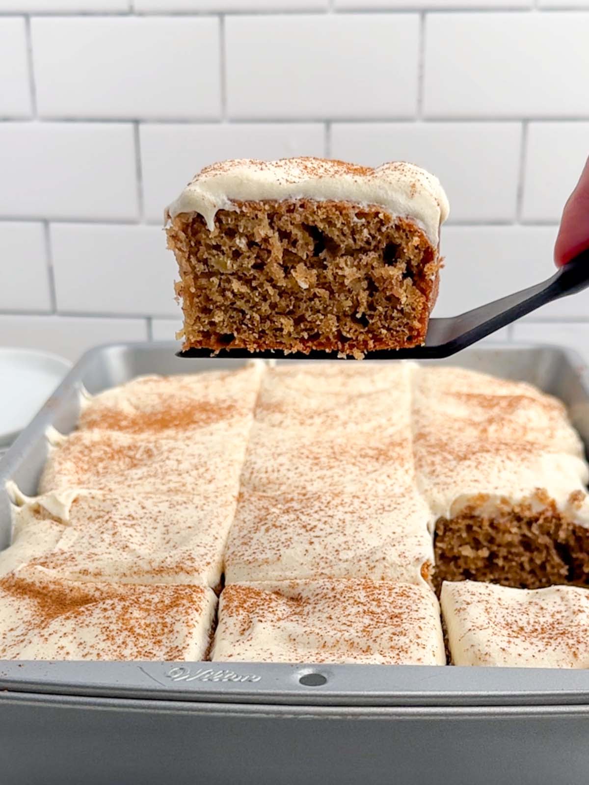 spatula lifting up a banana bar with cream cheese frosting out of the pan.