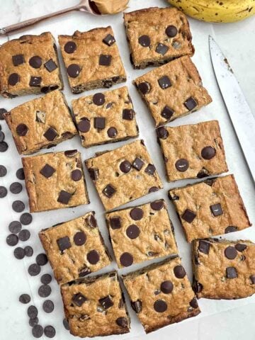 banana blondies cut into squares on white parchment paper.