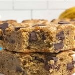 two banana blondies with the corner bites taken out stacked on a white plate.