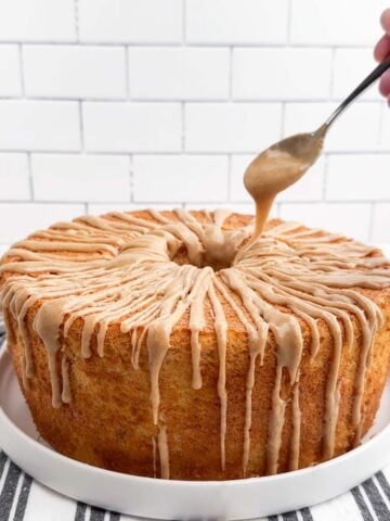 spoon drizzling cinnamon icing over banana cake.