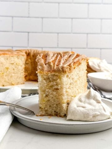 a piece of cake mix banana angel food cake with a bite removed on a plate with cinnamon whipped cream.