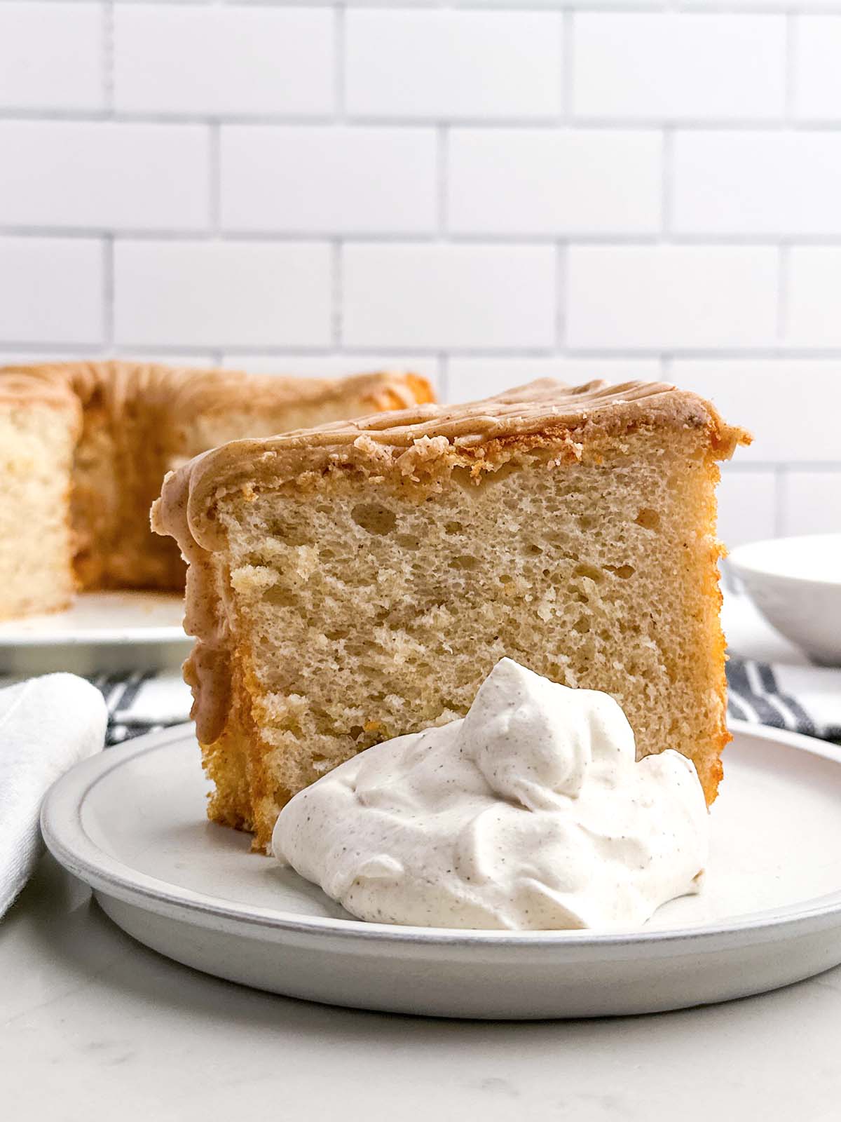a piece of cake mix banana angel food cake on a plate with cinnamon whipped cream.