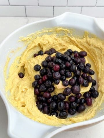 muffin batter and blueberries in a mixing bowl.
