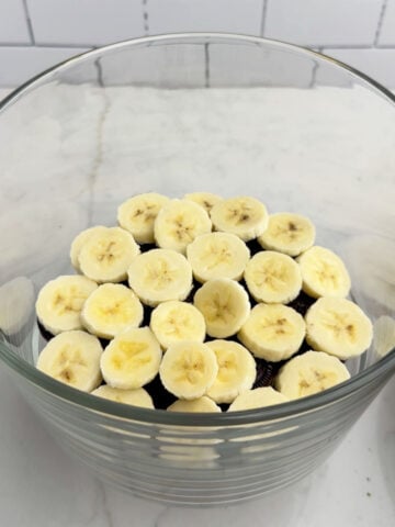 bananas layered over cookies in a clear trifle bowl.