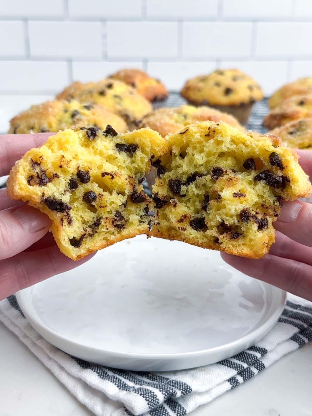 hands holding a chocolate chip cake mix muffin torn in half.