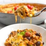 fork lifting up a gooey, cheesy bite of Mexican chicken and rice from a white bowl.