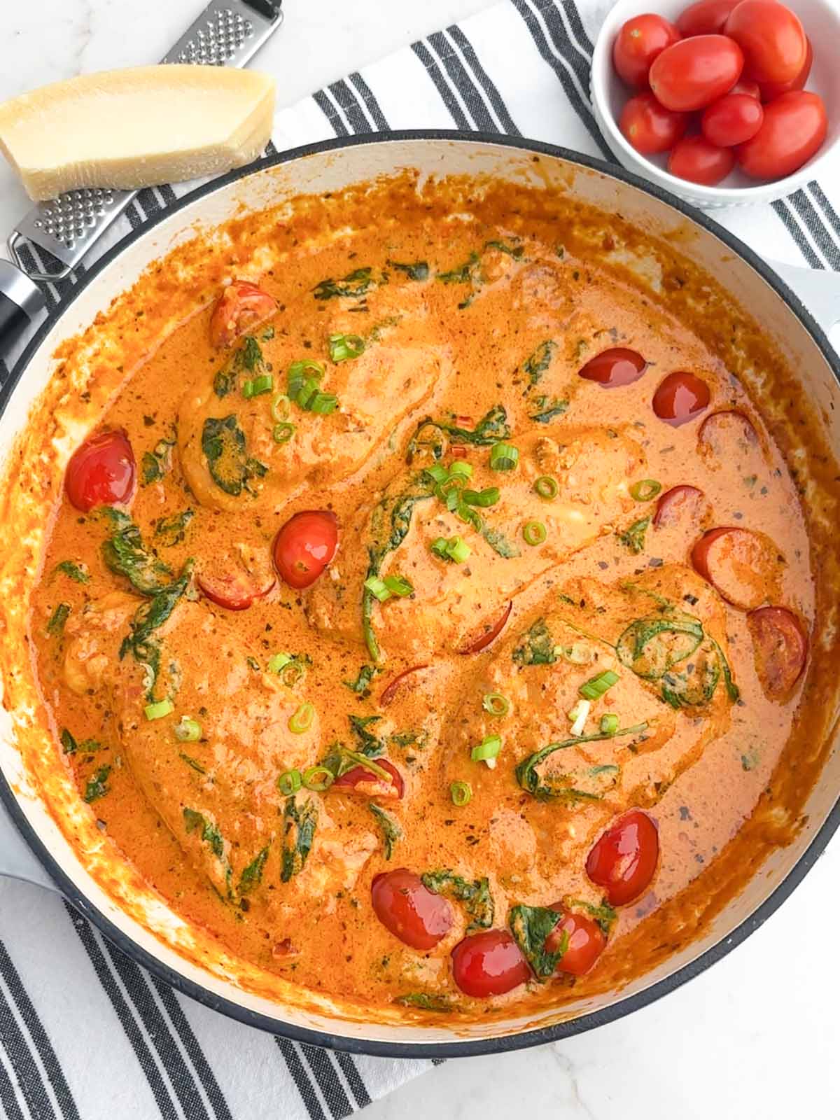 sundried tomato pesto chicken with spinach and tomatoes in a Dutch oven.
