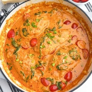 sundried tomato pesto chicken with spinach and tomatoes in a Dutch oven.