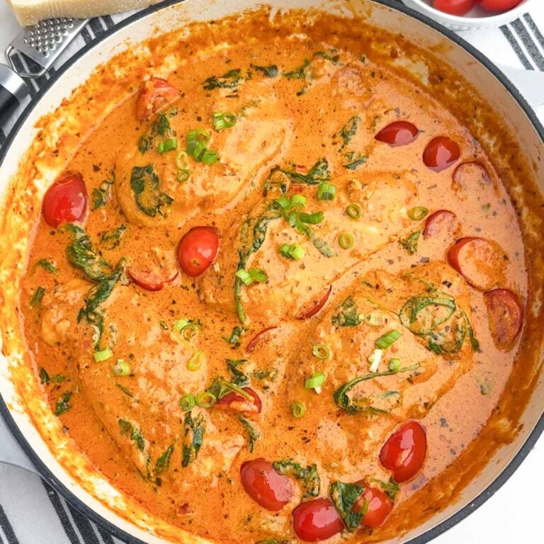 sundried tomato pesto chicken with spinach and tomatoes in a Dutch oven.