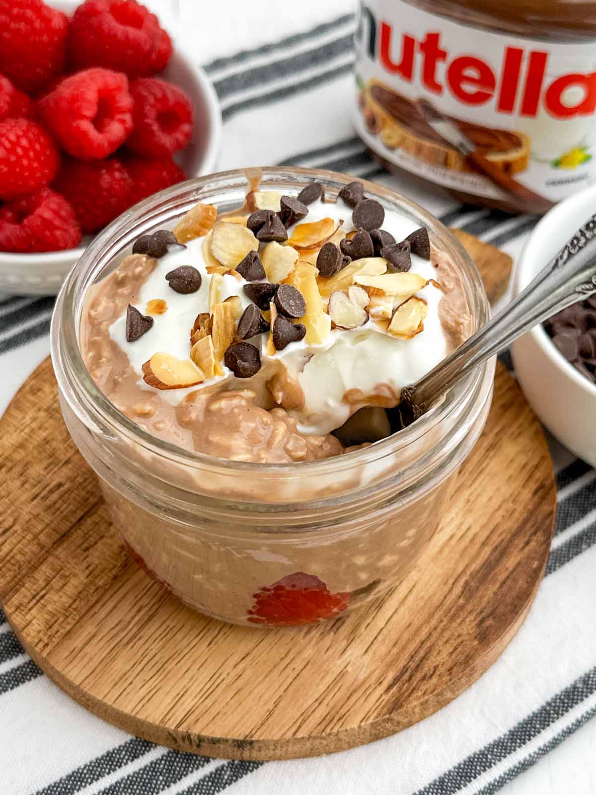 Nutella overnight oats topped with chocolate chips and nuts in a mason jar.