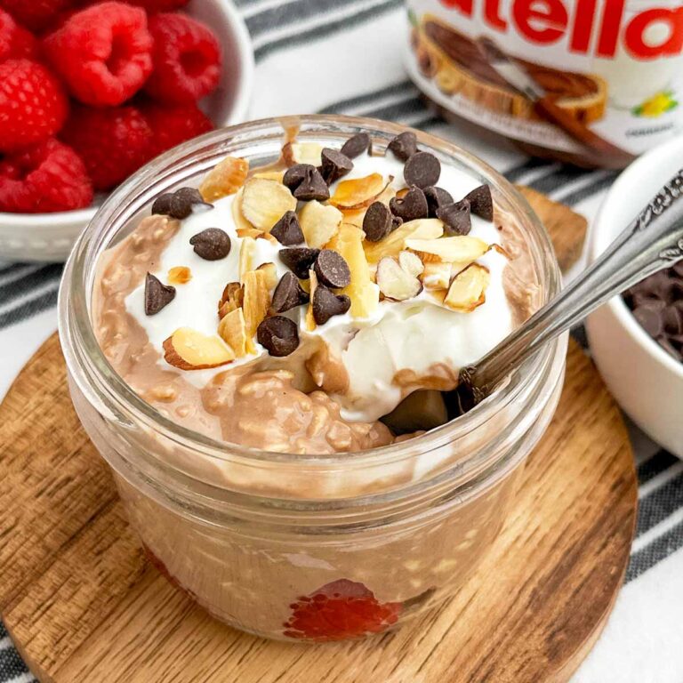 Nutella overnight oats topped with chocolate chips and nuts in a mason jar.