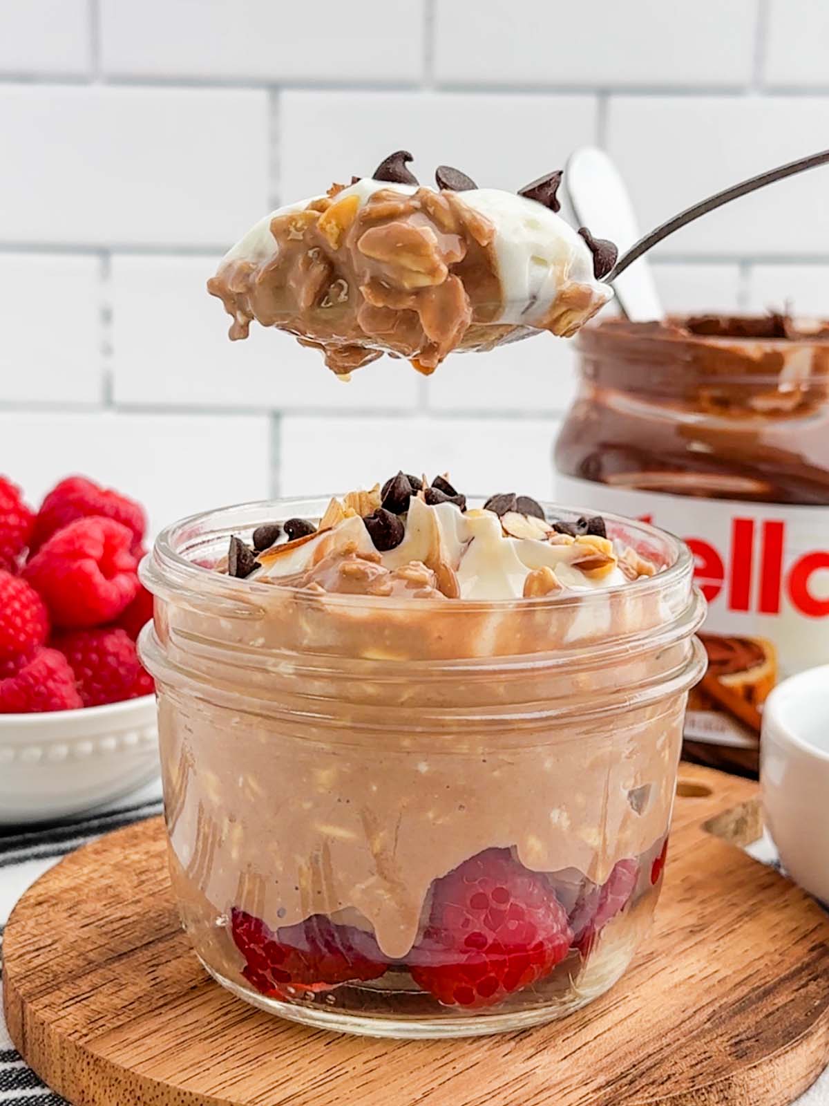 mason jar of Nutella overnight oats with a spoonful lifted above it.