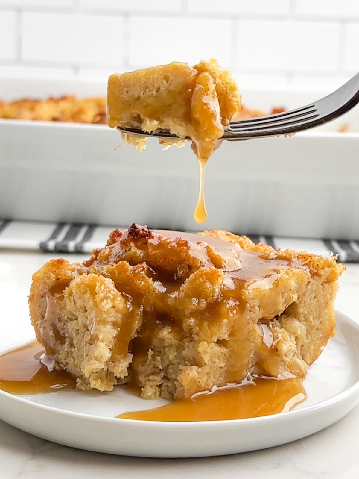 fork lifting up a bite of pineapple bread pudding with whiskey sauce.