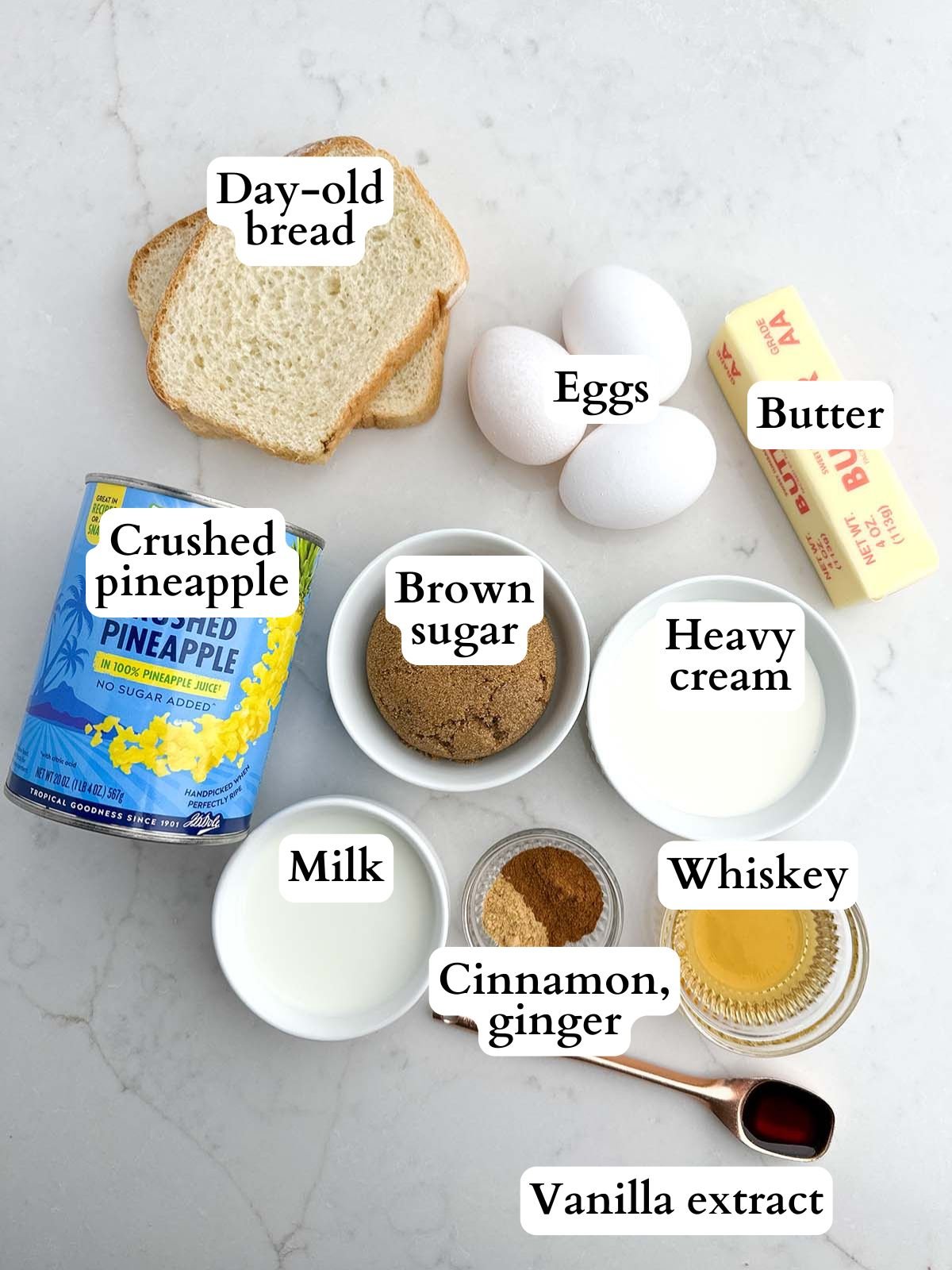 ingredients for pineapple bread pudding and caramel whiskey sauce on a white countertop.