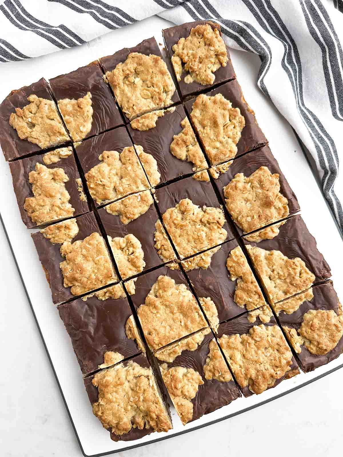 chocolate revel bars cut into squares on a white cutting board.