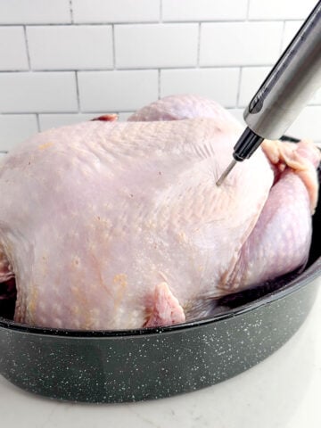 an injector piercing the skin of a raw turkey.