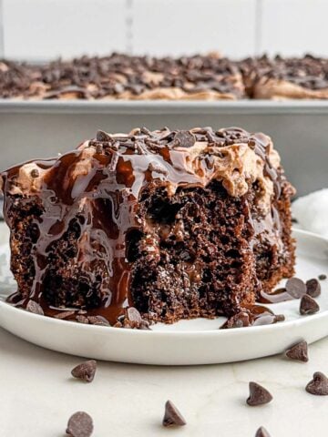 piece of chocolate poke cake on a white plate.