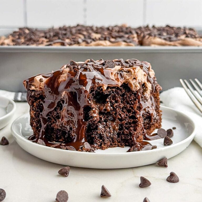 piece of chocolate poke cake on a white plate.